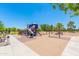 View of the playground area featuring climbing structures, swings, and shade trees at 42577 W Rosalia Dr, Maricopa, AZ 85138