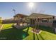 Landscaped backyard with green turf, a pergola with seating, and a young tree at 4588 W Suncup Dr, San Tan Valley, AZ 85144