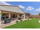 Well-manicured backyard featuring a covered patio, outdoor seating, dining area, barbecue grill, and lush artificial grass at 4887 N 184Th Ln, Goodyear, AZ 85395