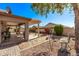 Backyard featuring a covered patio area with seating, landscaping, and gravel ground cover at 674 S 231St Dr, Buckeye, AZ 85326