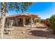 Exterior view of the house with a covered patio, garden area, and gravel landscaping in backyard at 674 S 231St Dr, Buckeye, AZ 85326