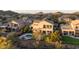 Aerial view of a home with a backyard pool and spa nestled in a lush neighborhood with mountain views at sunset at 7357 E Rochelle Cir, Mesa, AZ 85207