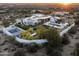 Aerial view of a modern estate with a pool, sports court, and desert landscaping at sunset at 8822 E Chino Dr, Scottsdale, AZ 85255