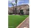 Lush front yard featuring artificial grass, palm trees, and tidy decorative rock landscaping at 9765 E Lompoc Ave, Mesa, AZ 85209