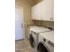 Functional laundry room equipped with modern washer and dryer, utility sink, and ample storage cabinets at 9765 E Lompoc Ave, Mesa, AZ 85209