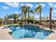 An inviting pool is surrounded by lush landscaping and swaying palm trees creating a backyard oasis at 9765 E Lompoc Ave, Mesa, AZ 85209