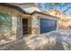 Charming single-story home featuring a blue garage door, desert landscaping, and secure front entry at 10594 E Wallflower Ln, Florence, AZ 85132