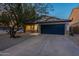 Attractive single-story home with a blue garage door and desert landscaping, situated on a spacious lot at 10594 E Wallflower Ln, Florence, AZ 85132