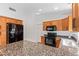 Well-lit kitchen featuring wooden cabinets, granite countertops, and black appliances at 1148 S Sierra St, Gilbert, AZ 85296