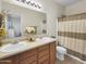 Well-lit bathroom with double sink vanity, framed mirror, and shower-tub combo with tan and white striped curtain at 12017 N 151St Dr, Surprise, AZ 85379