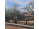 View from the street with an iron fence, desert flora, and a tile roofed house in the background at 12946 N 116 St # 24, Scottsdale, AZ 85259