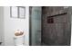 Sleek bathroom featuring dark tile, a glass shower, and a toilet with toilet paper in a basket at 13451 S 47Th Way, Phoenix, AZ 85044