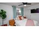 Bright bedroom features a ceiling fan, mounted television, and window with stylish teal curtains at 13451 S 47Th Way, Phoenix, AZ 85044