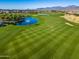 Aerial view of a lush green golf course with mature trees and a scenic lake in the background at 17192 W Rocklin St, Surprise, AZ 85388