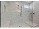 Close-up of walk-in shower with marble tile surround, rainfall shower head, and bench at 17192 W Rocklin St, Surprise, AZ 85388