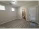 View of an empty bedroom featuring light gray plank flooring, three windows, and an ensuite bathroom at 1743 W Pollack St, Phoenix, AZ 85041