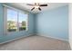 Bright bedroom with a large window, ceiling fan, and light blue painted walls at 17813 W Primrose Ln, Surprise, AZ 85374