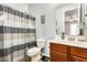 Bathroom featuring neutral cabinets, striped shower curtain, and a mirror with decorative accessories at 18256 W Carol Ave, Waddell, AZ 85355