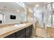 Bathroom featuring dual sink vanity, glass enclosed shower, and tan marble flooring at 18256 W Carol Ave, Waddell, AZ 85355