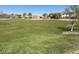 Large green lawn in a community park with playground, covered picnic tables, and distant neighborhood houses at 18823 N Avelino Dr, Maricopa, AZ 85138