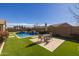 Beautifully landscaped backyard featuring artificial turf, desert landscaping, a pool, and an outdoor dining area at 1899 E Everglade Ln, Gilbert, AZ 85298