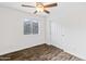 This cozy bedroom features a ceiling fan, wood floors, and a window with natural light at 1911 E Hartford Ave, Phoenix, AZ 85022