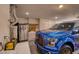 View of garage with cabinets, work bench, and large, blue pickup truck parked inside at 19460 N Hidden Canyon Dr, Surprise, AZ 85374