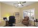 Home office with large window, ceiling fan, desk, and ample storage at 19460 N Hidden Canyon Dr, Surprise, AZ 85374