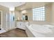 Bright bathroom featuring glass block shower and a garden tub next to the vanity at 2029 N 109Th Ave, Avondale, AZ 85392