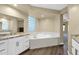 Bright bathroom features a luxurious soaking tub and granite countertop vanity at 2029 N 109Th Ave, Avondale, AZ 85392