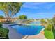 Backyard pool with lush landscaping overlooks tranquil lake, offering a serene outdoor space at 2029 N 109Th Ave, Avondale, AZ 85392