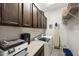 Well-lit laundry room featuring dark wood cabinets, countertop space, and modern washer and dryer units at 2046 N Red Clf, Mesa, AZ 85207