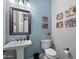 Stylish powder room with a pedestal sink, modern mirror, and unique wall art at 2046 N Red Clf, Mesa, AZ 85207