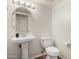 Stylish half-bath with a pedestal sink, oval mirror, and modern fixtures at 2406 W Tallgrass Trl, Phoenix, AZ 85085