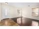 Bright living room featuring dark hardwood floors, a window with blinds, and a white front door at 2406 W Tallgrass Trl, Phoenix, AZ 85085