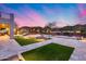 Backyard featuring pool, grassy area, stone patios, and lush landscaping with serene sunset in the background at 28826 N 67Th Dr, Peoria, AZ 85383