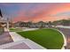 Backyard featuring stone patios, manicured lawn, professional landscaping, and an outdoor living space at sunset at 28826 N 67Th Dr, Peoria, AZ 85383