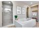 Bright bathroom with glass shower and a large soaking tub with tiled surround at 28826 N 67Th Dr, Peoria, AZ 85383