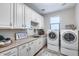 Bright laundry room with tan countertops, white cabinets, sink, and modern washer and dryer appliances at 28826 N 67Th Dr, Peoria, AZ 85383