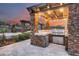 An outdoor kitchen featuring stone counter tops, a stainless steel grill, and integrated appliances at sunset at 28826 N 67Th Dr, Peoria, AZ 85383