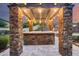 An outdoor kitchen featuring stone counter tops, a stainless steel grill, and integrated appliances at sunset at 28826 N 67Th Dr, Peoria, AZ 85383