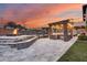 Beautiful outdoor kitchen and fire pit with stone accents and patio under colorful sky at 28826 N 67Th Dr, Peoria, AZ 85383