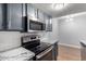 Kitchen features stainless steel microwave above a black stove and gray cabinets with modern, white subway tile backsplash at 3416 N 44Th St # 70, Phoenix, AZ 85018