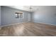 Open living room with wood-look flooring, modern gray walls, natural light from the window, and a ceiling fan at 3545 N Hohokam Dr, Eloy, AZ 85131