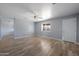 Expansive living room with wood-look flooring, modern gray walls, a ceiling fan, and natural light from the windows at 3545 N Hohokam Dr, Eloy, AZ 85131