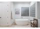 Elegant soaking tub featuring travertine flooring, a glass block window, and desert art at 35530 N Canyon Crossings Dr, Cave Creek, AZ 85331