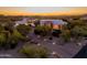 Stunning exterior view of a custom home with desert landscaping and lit driveway at sunset at 35530 N Canyon Crossings Dr, Cave Creek, AZ 85331