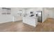 Open kitchen with an island and stainless steel appliances; seamlessly connected to the living area with wood-look tile flooring at 4513 W 95Th Dr, Tolleson, AZ 85353