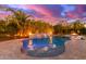 Stunning backyard pool with waterfall feature, lush landscaping, and outdoor lighting at 4675 S Bandit Rd, Gilbert, AZ 85297