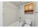 Clean bathroom featuring a shower and bathtub combo, toilet, and wooden cabinets for storage at 510 N Alma School Rd # 103, Mesa, AZ 85201